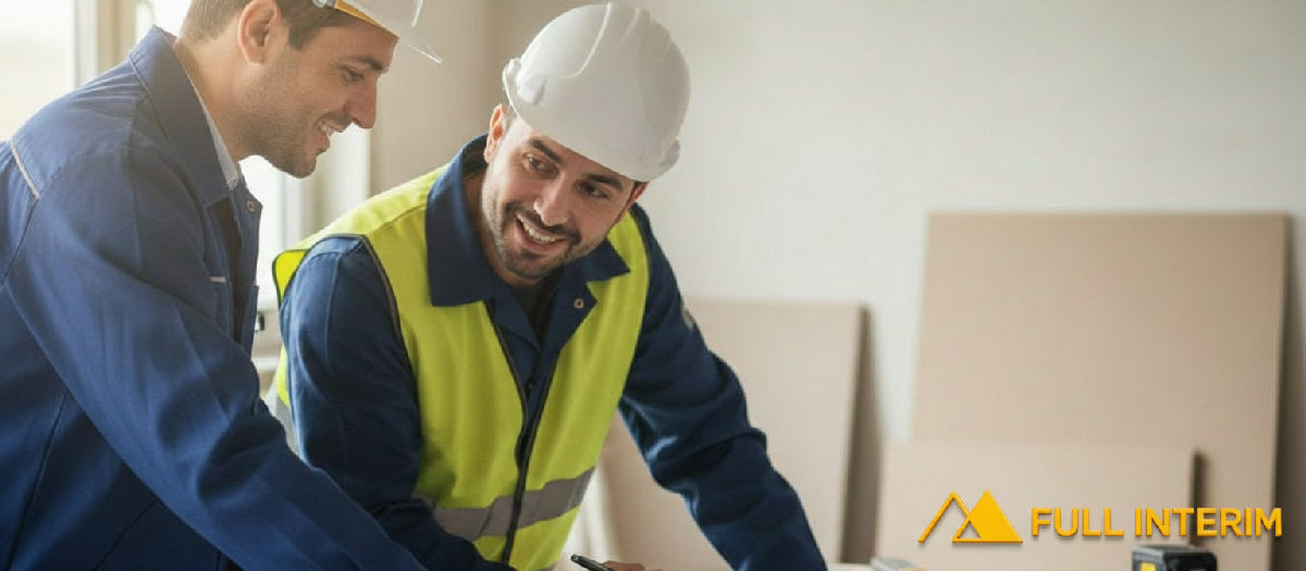 Chef de chantier et plaquiste roumain discutent autour d'un plan.